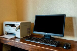Configuración de computadora de escritorio con una impresora Samsung, un monitor HP, un teclado Compaq y un ratón sobre un escritorio de madera.