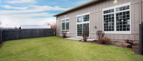 A modern building with large windows, a well-maintained lawn, and a wooden fence.
