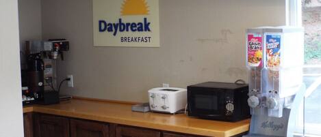 A breakfast area with a coffee machine, toaster, microwave, and cereal dispensers.