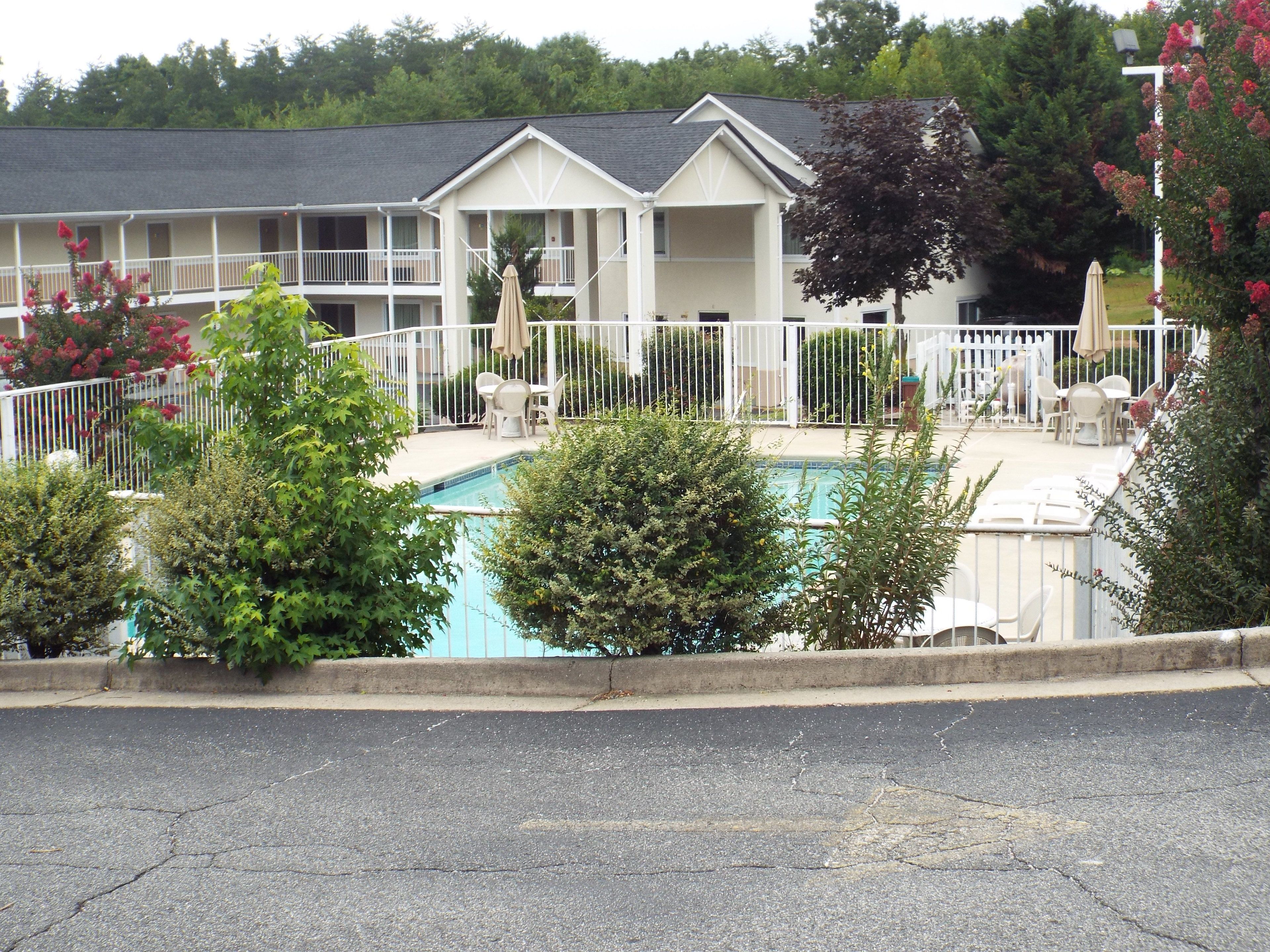 Um motel com piscina, área de estar externa e um pátio cercado.