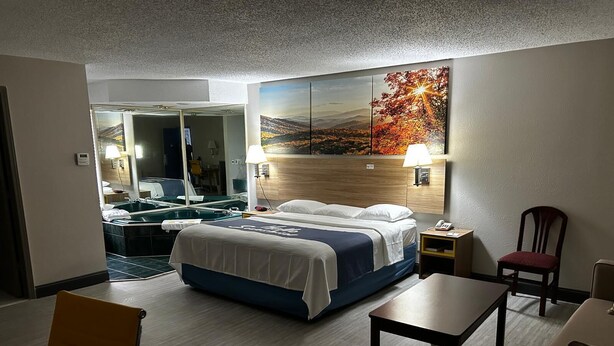 Ein Hotelzimmer mit Bett, Schreibtisch, Stuhl, Badezimmer mit Spiegel und Waschbecken sowie einem Bild an der Wand.