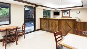 Ein Restaurant mit Holztischen, einer Theke und einem Fernseher an der Wand.