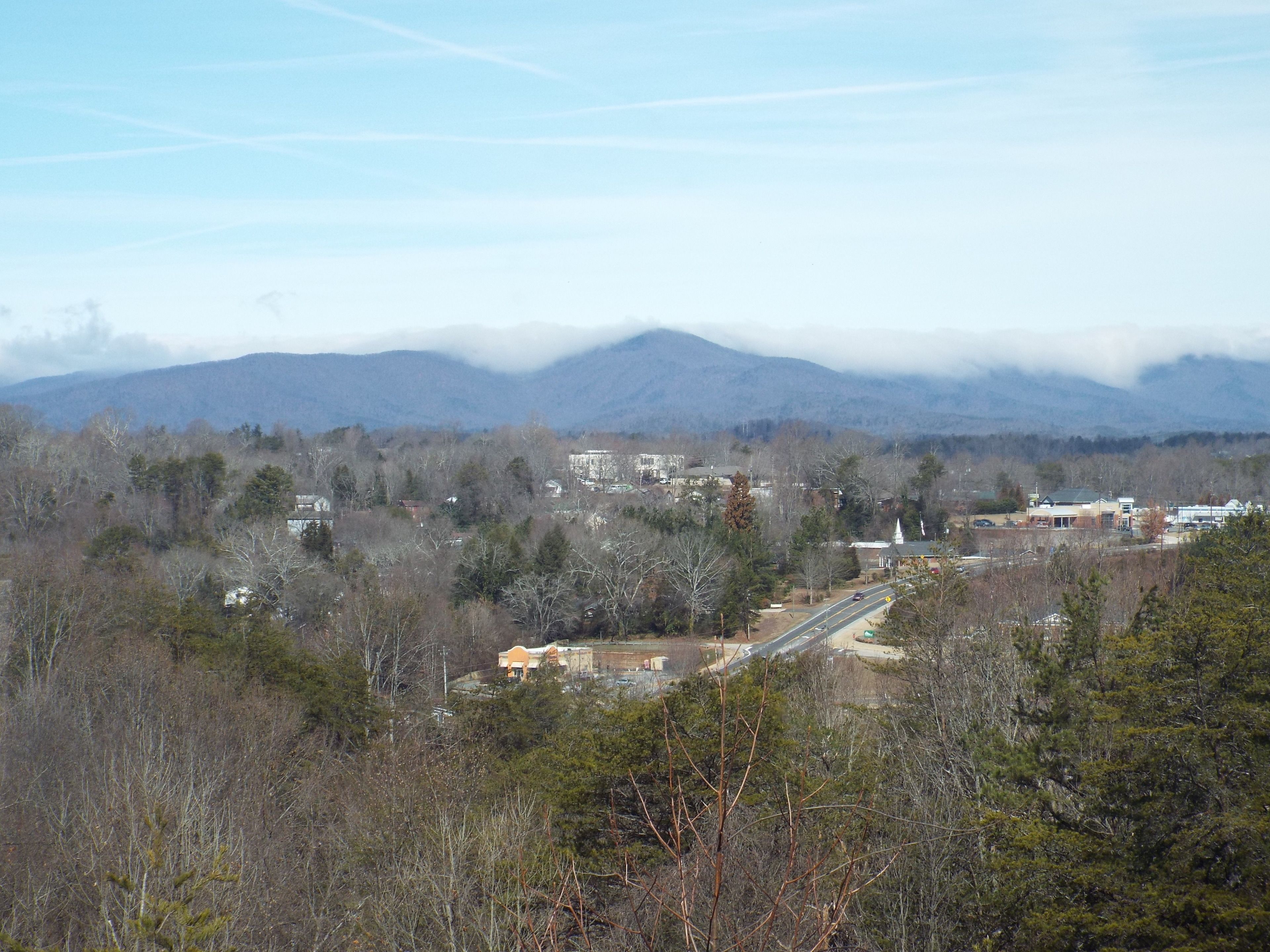 A town with a prominent church, surrounded by mountains and dense forests.