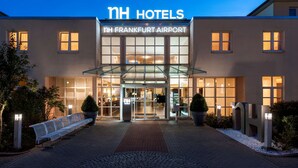 A hotel with a modern facade, a glass entrance, and a sign indicating it's located at Frankfurt Airport. - NH Frankfurt Airport (Kelsterbach)