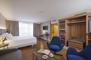 Una habitación de hotel con cama, escritorio, silla, mesa de centro y armario.