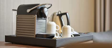 Une machine à café sur un plateau, avec deux tasses blanches et une bouilloire.