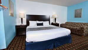 Ein Hotelzimmer mit einem großen Bett, zwei Nachttischen mit Lampen, einem gemusterten Sofa und einer blauen Wand.
