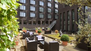 A courtyard with outdoor seating, a small garden, and a building with multiple windows and a staircase. - Amrâth Grand Hotel de l'Empereur (Maastricht)
