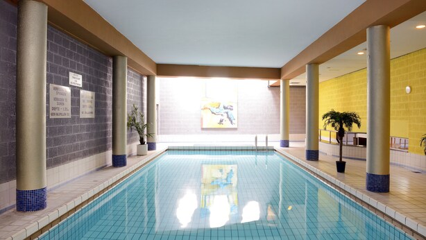 An indoor swimming pool with clear water, surrounded by walls with tiled columns and a ceiling with recessed lighting. - Amrâth Grand Hotel de l'Empereur (Maastricht)