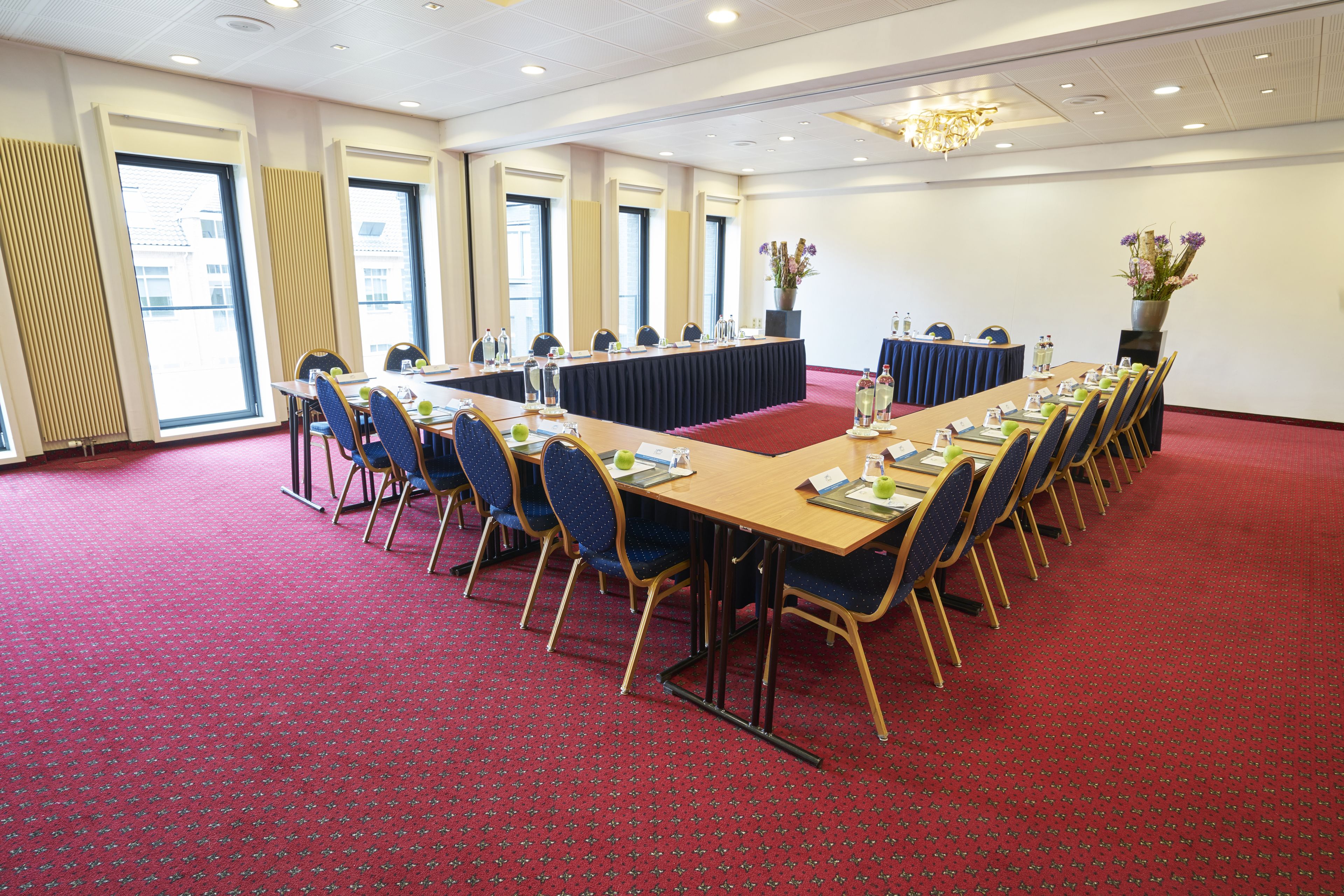 A conference room with a long table, chairs, and a red carpet.