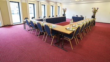 A conference room with a long table, chairs, and a red carpet.