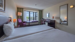 A hotel room with a large bed, a desk, a chair, and a window with a view. - Amrâth Grand Hotel de l'Empereur (Maastricht)