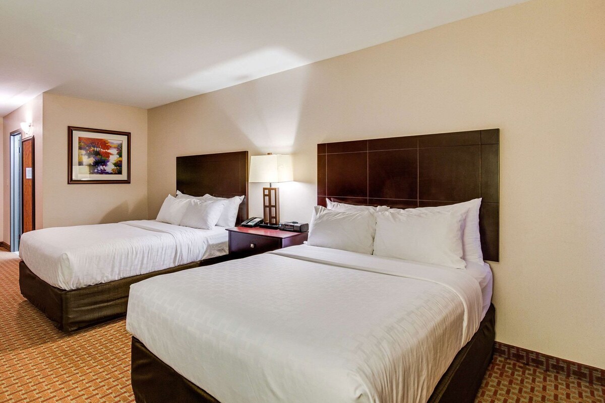 Two twin beds with wooden headboards, a bedside table with a lamp, and a framed picture on the wall.