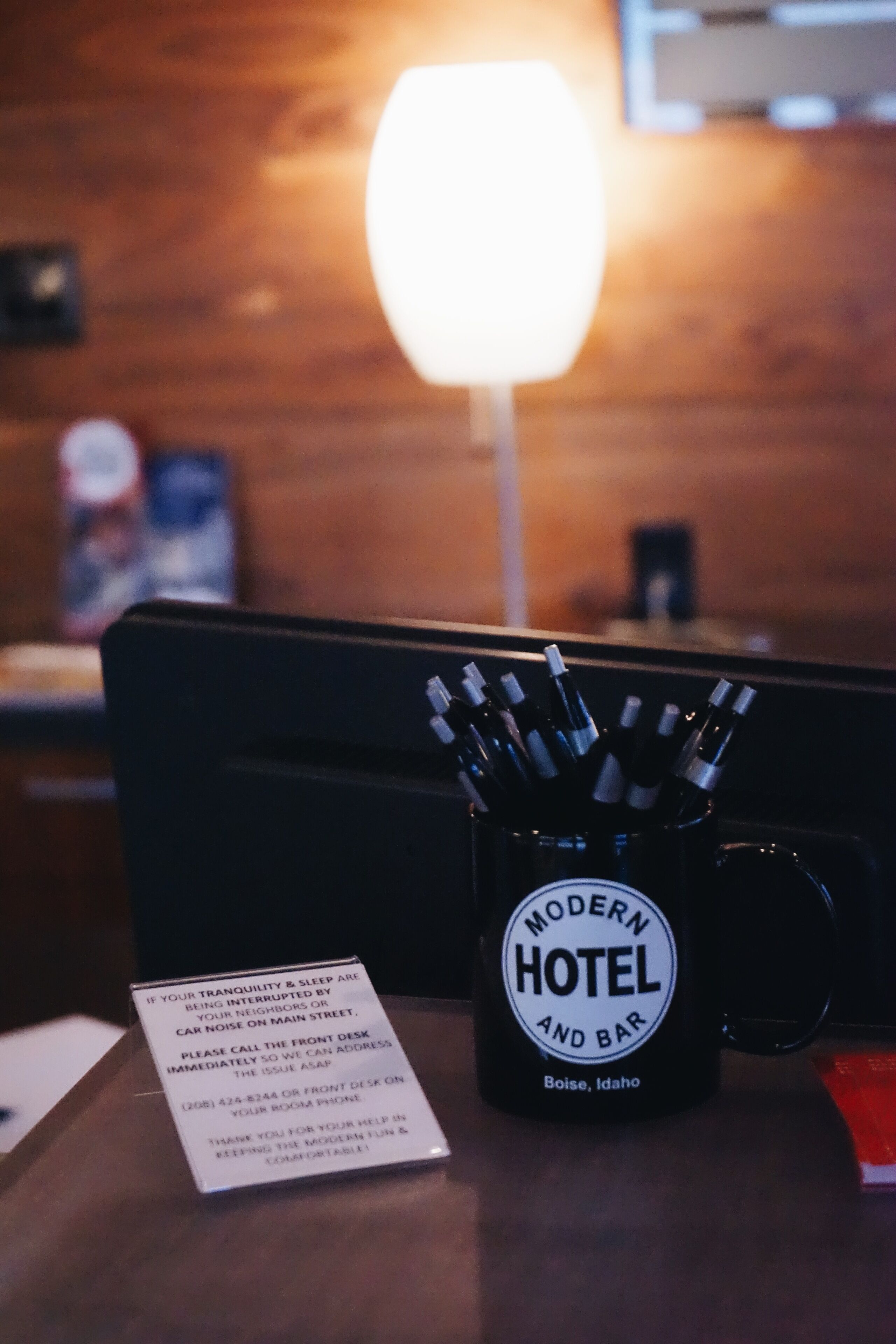 A black mug with "Modern Hotel and Bar" text, a menu, and a sign about noise disturbance.