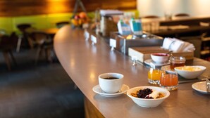 Una barra de desayuno con café, jugo de naranja y tazones de cereal.