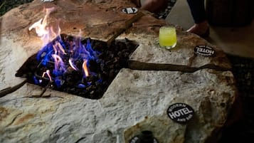 Mesa de piedra con una chimenea y un vaso de bebida amarilla.