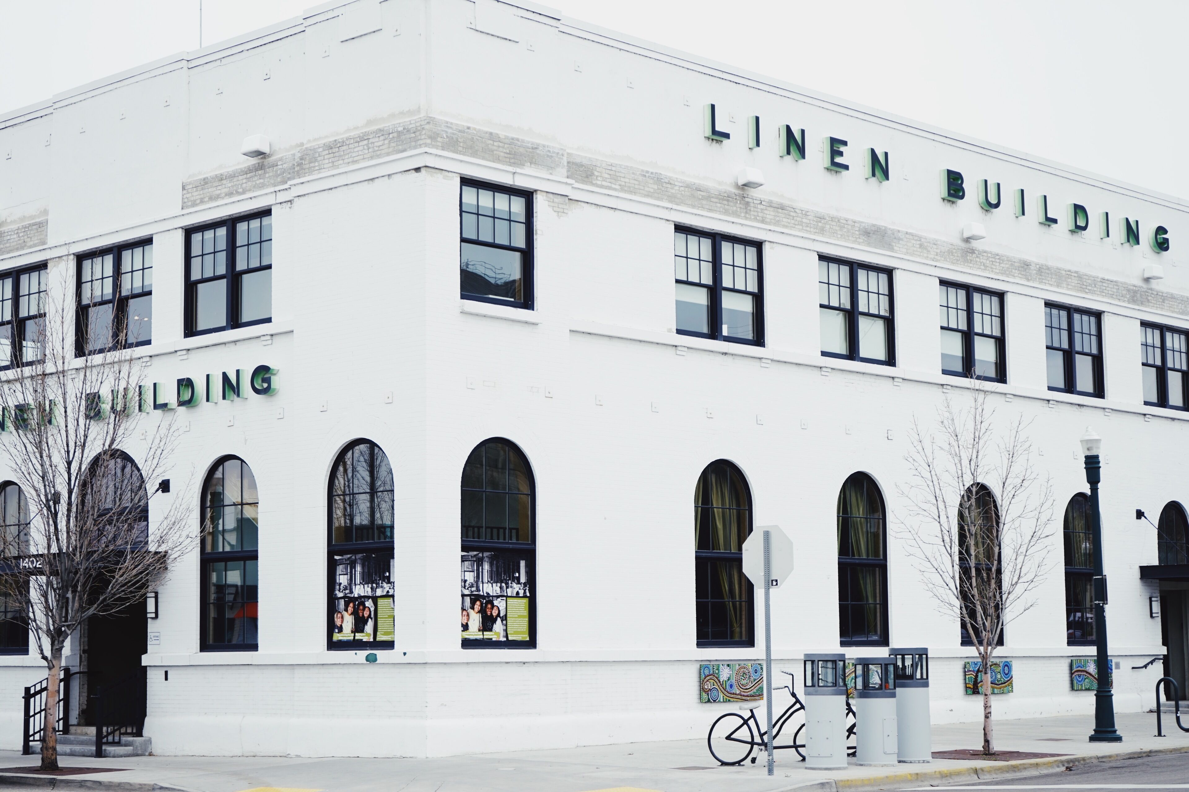 A white building with arched windows and the name "LINEN BUILDING" on the facade.