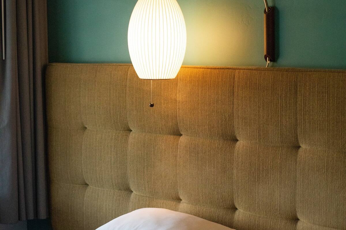 A bed with a tufted headboard, a bedside lamp, and a patterned throw blanket.