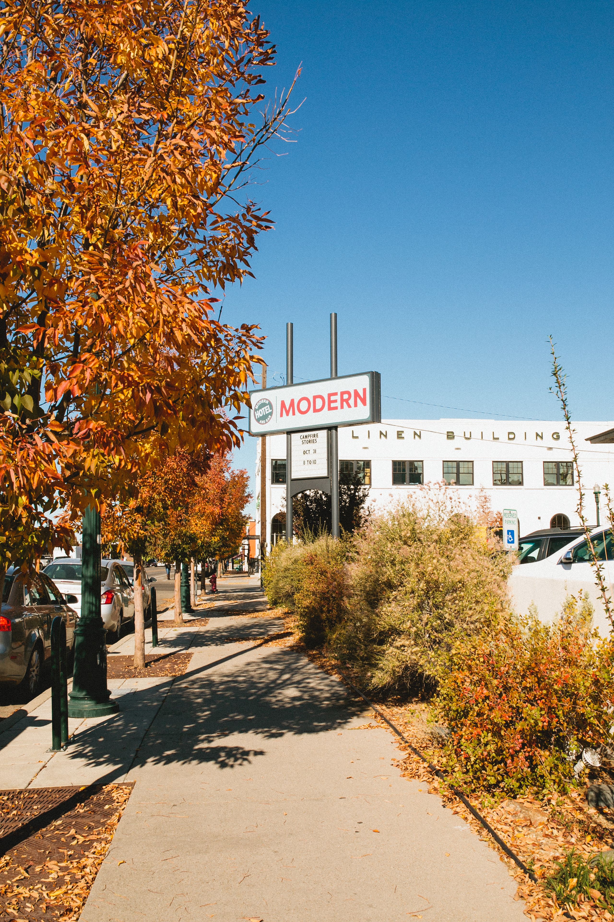 A building with a sign that reads "MODERN LINEN BUILDING" and a parking lot with cars.