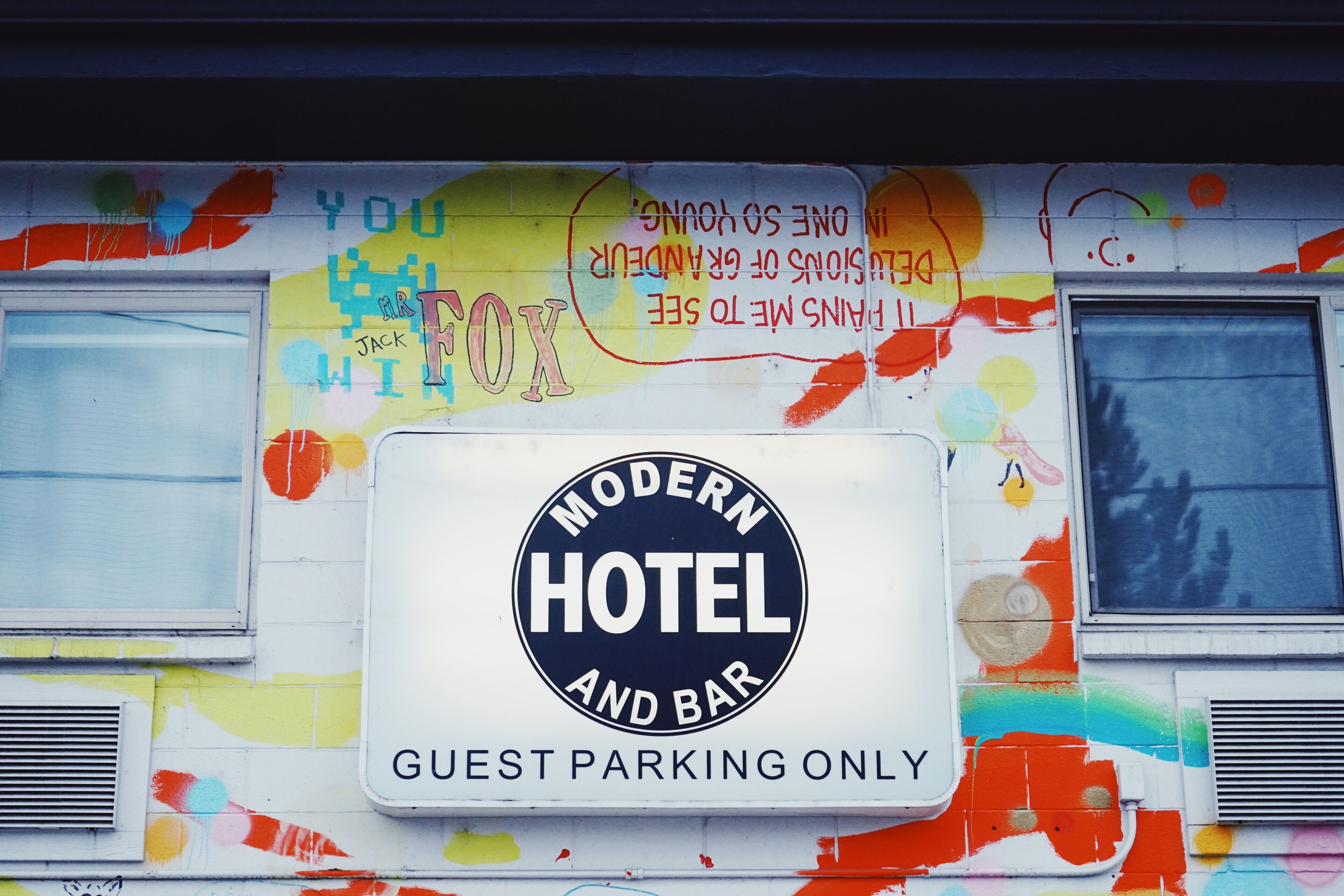Un mur avec une enseigne indiquant « Hôtel et bar moderne » et une autre indiquant « Stationnement réservé aux clients ».
