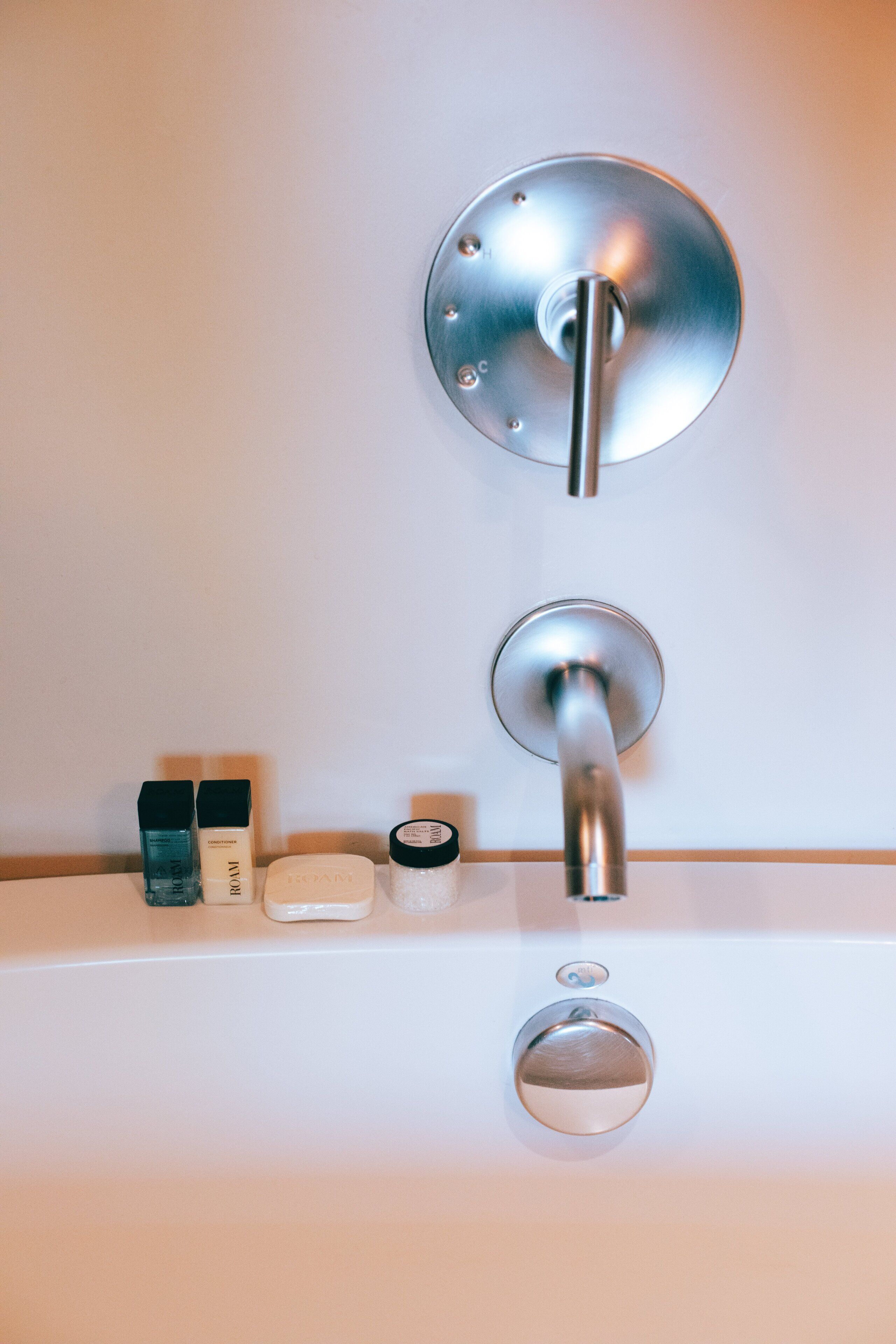 Un baño con un grifo moderno, un dispensador de jabón y una botella de jabón de manos en la encimera.