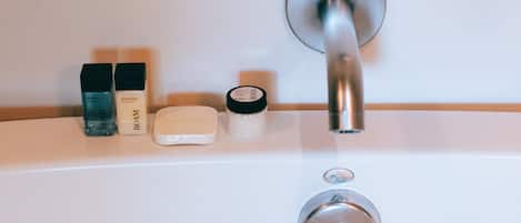 A bathroom with a modern faucet, a soap dispenser, and a bottle of hand soap on the counter.