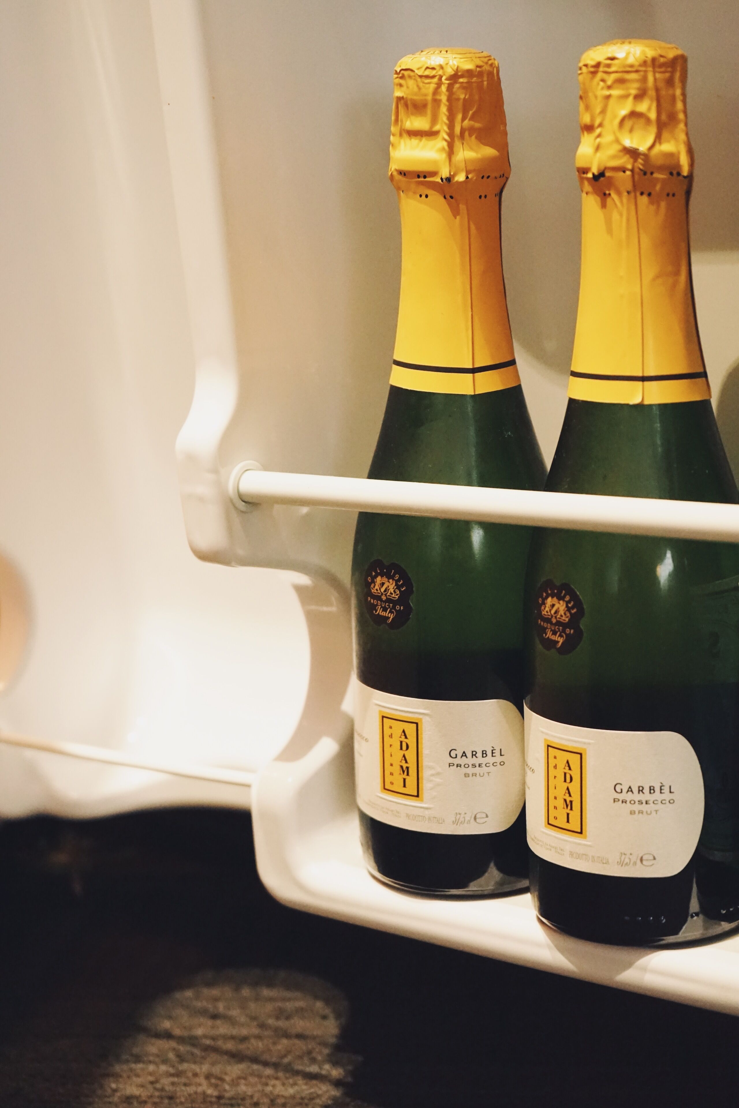 Deux bouteilles de vin Adami Prosecco Brut dans un réfrigérateur.