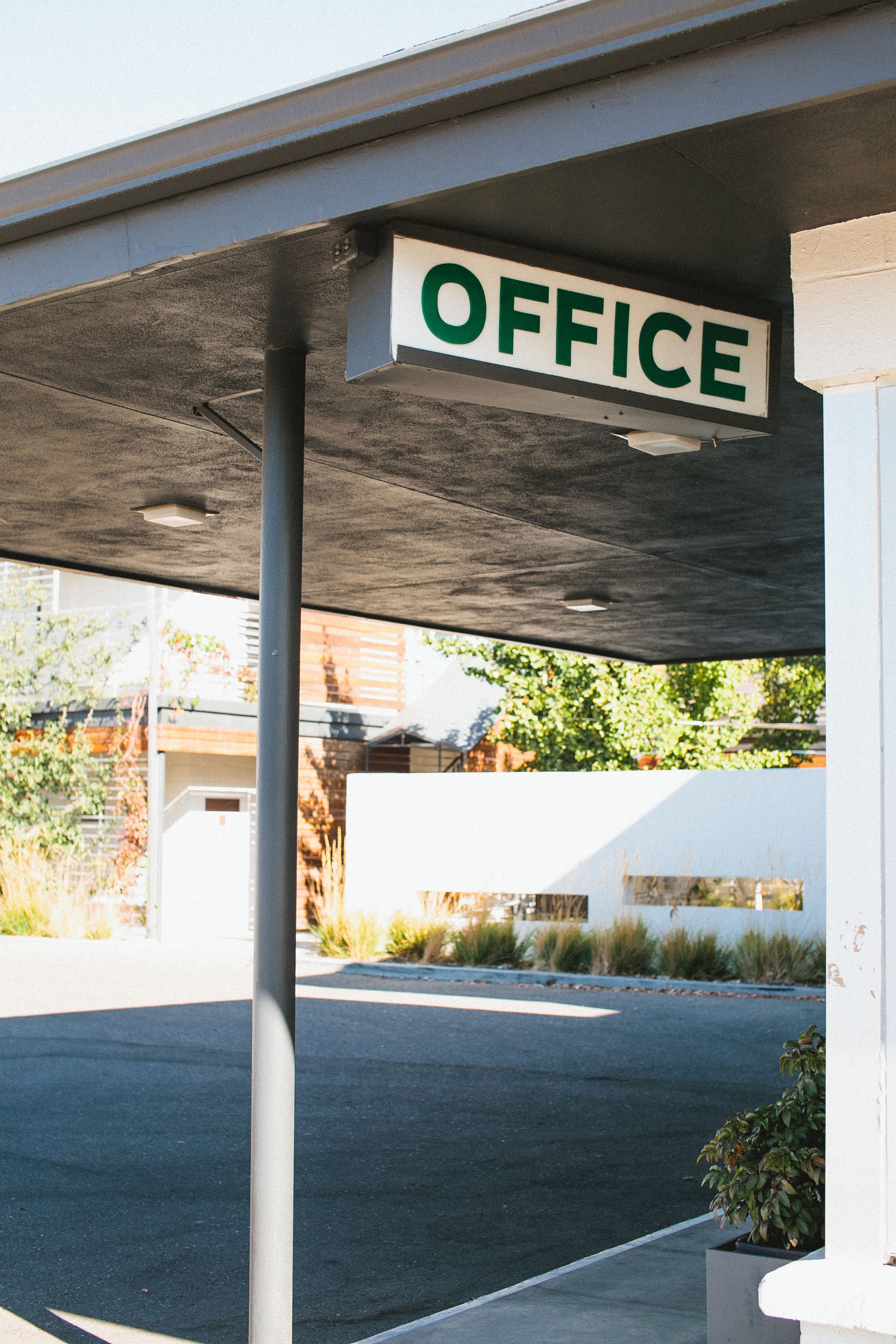 A building with a sign that reads "OFFICE" under a covered area.