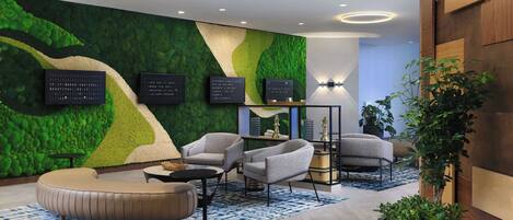 Un lobby moderno con una pared verde, un área de estar y una recepción.