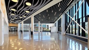 Un hall d’entrée spacieux, doté d’un plafond au design moderne, de grandes fenêtres et d’un plancher poli.