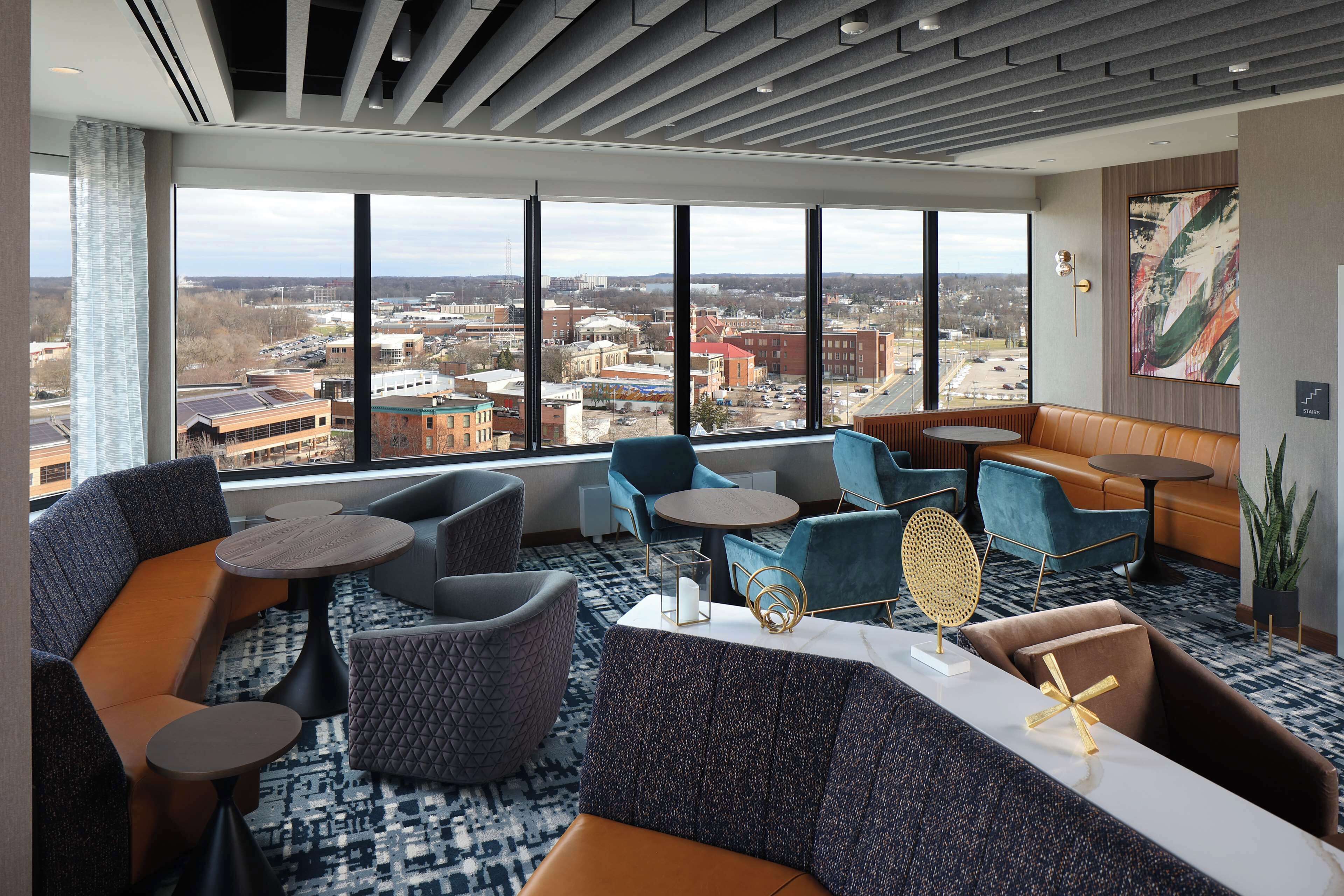 A modern hotel lobby with large windows, comfortable seating, and a city view.