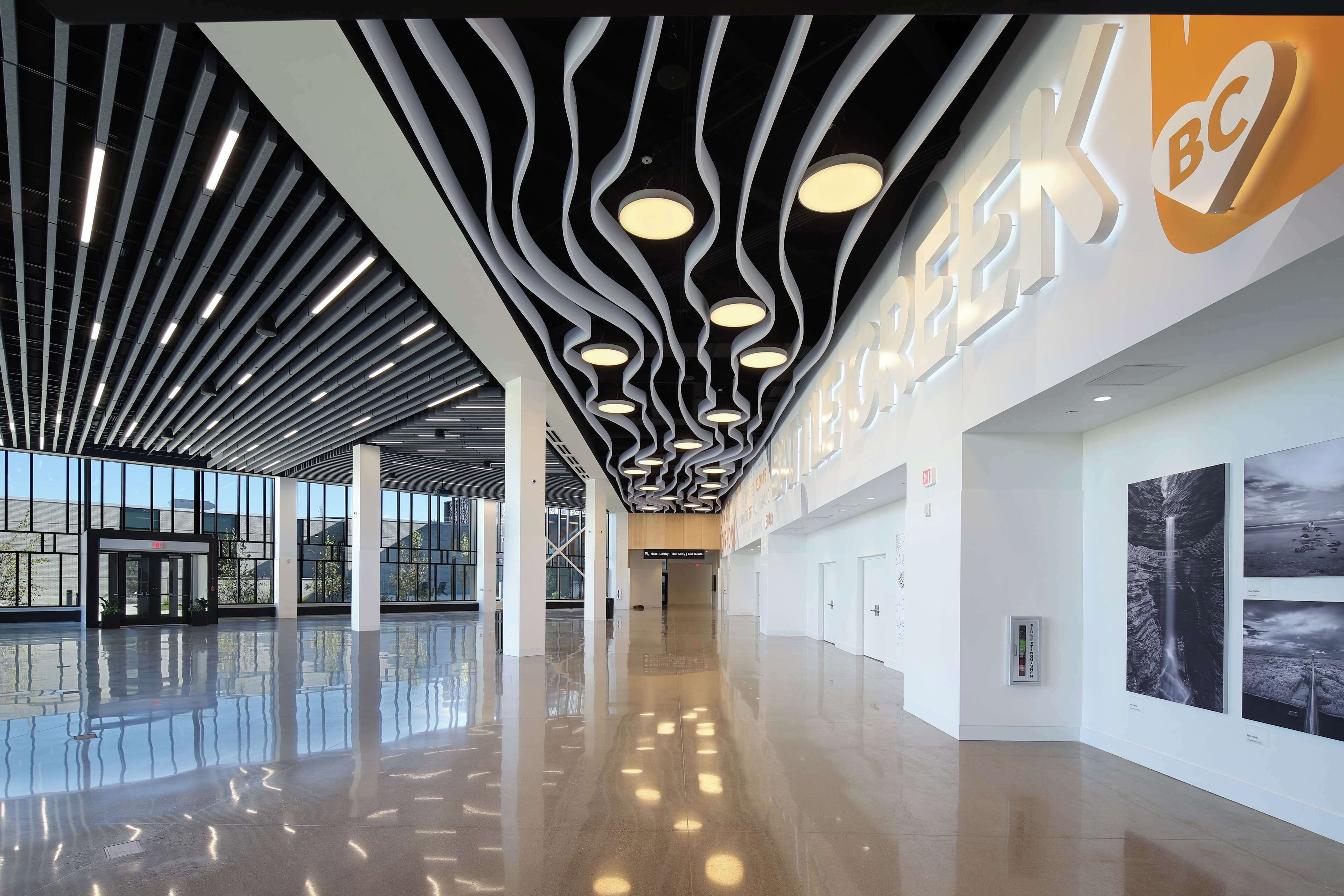 A spacious, modern interior with a sleek ceiling design, large windows, and a clean, reflective floor.