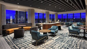 Un hall d’hôtel moderne offrant une vue panoramique sur la ville, avec des sièges confortables et un espace bar.