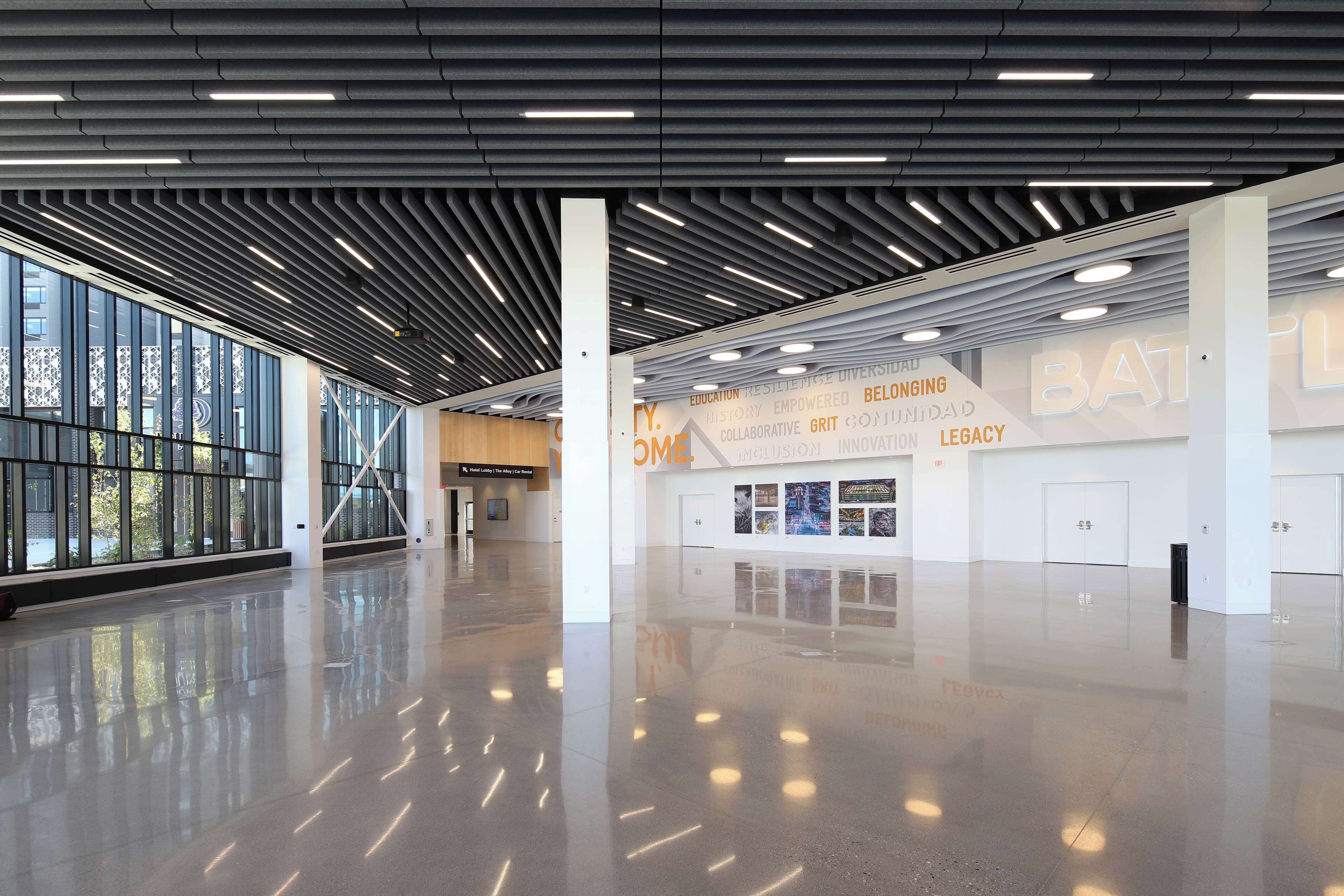 A spacious, modern interior with a high ceiling, large windows, and a polished floor.