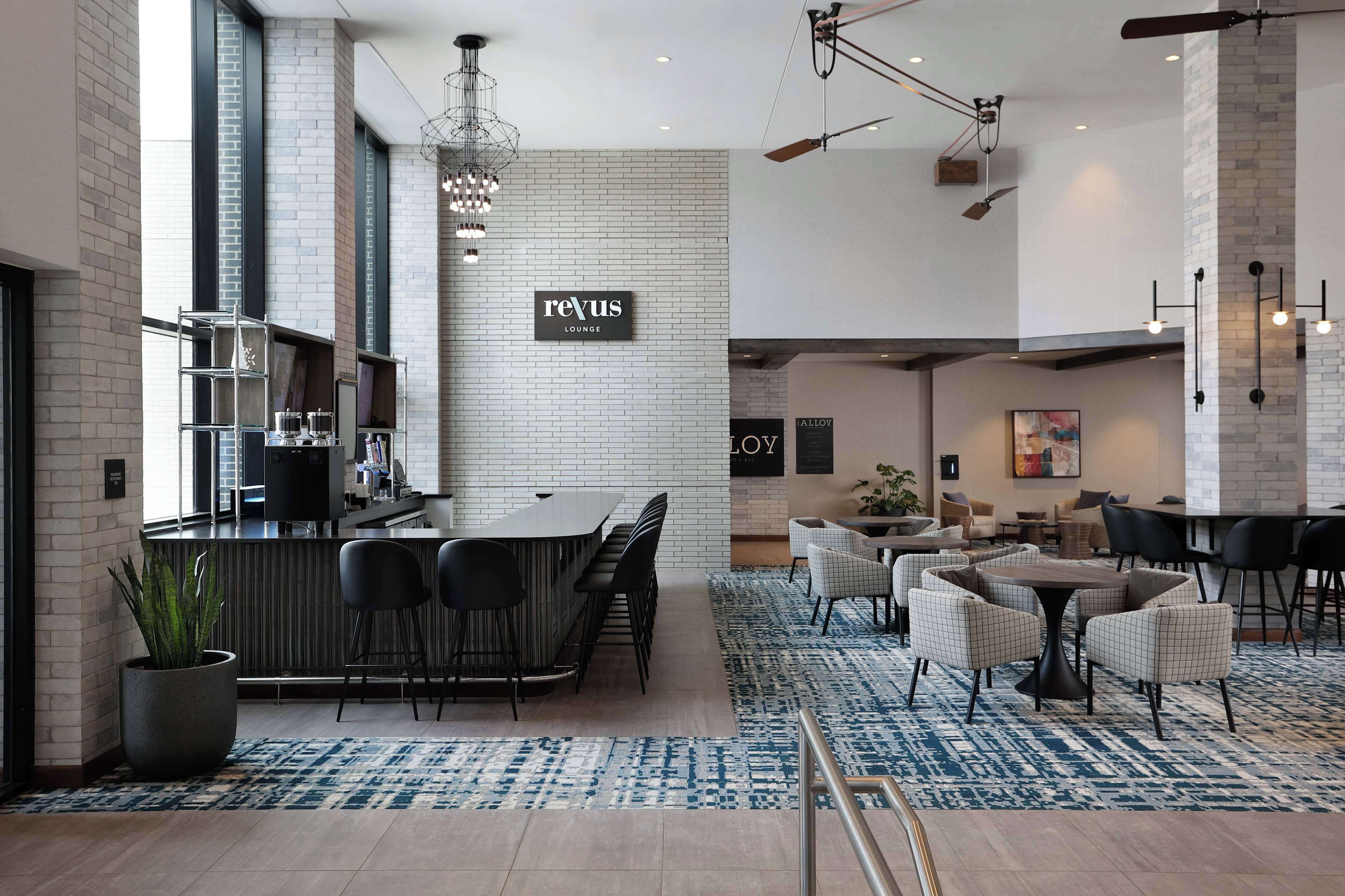 Un espace lounge moderne doté d’un bar, de sièges et d’une enseigne indiquant « reVus Lounge ».