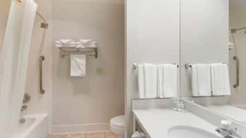 Une salle de bain moderne avec une baignoire, des toilettes et un lavabo. On y trouve plusieurs serviettes blanches et un porte-serviettes.