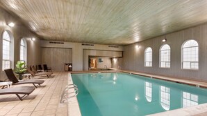 Una piscina interior con sillas de descanso y techo de madera.