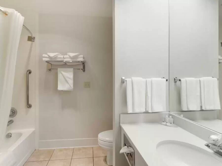 A modern bathroom with a bathtub, toilet, and a large mirror.