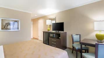A hotel room with a bed, a desk, a chair, a television, and a microwave.