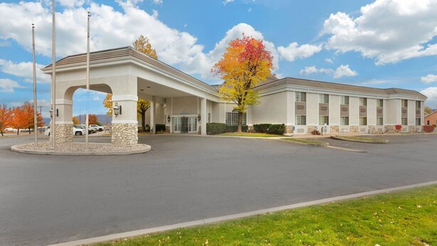 A hotel with a covered entrance, stone pillars, and a parking lot.