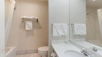 Un baño moderno con bañera, inodoro y un espejo grande.