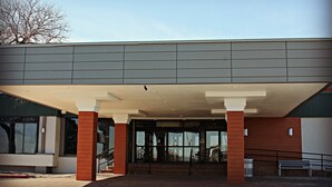 A building entrance with a covered walkway, large windows, and a staircase leading inside. - Plaza Hotel Denver (Denver)