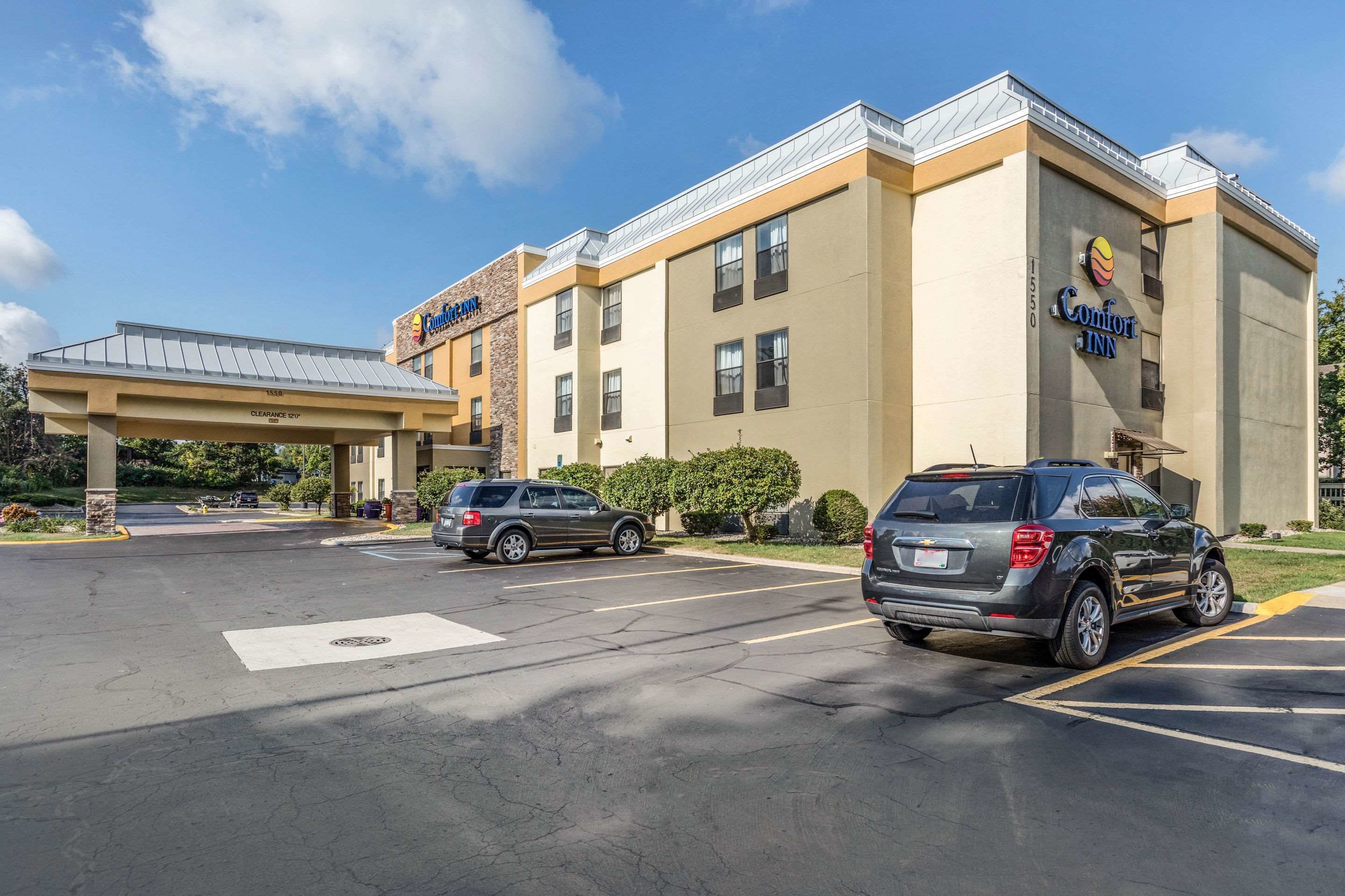Et Comfort Inn hotel med parkeringsplads, et overdækket indgangsparti og en klar himmel.
