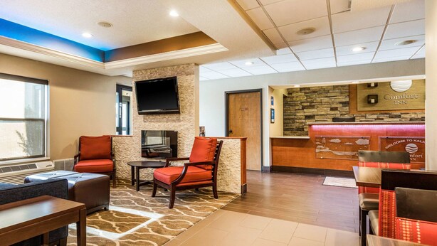 A hotel lobby with seating areas, a reception desk, and a television mounted on the wall. - Comfort Inn Wings Stadium (Kalamazoo)