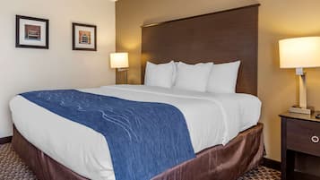 Habitación de hotel con una cama grande, dos lámparas fijadas a la pared y un cuadro enmarcado.