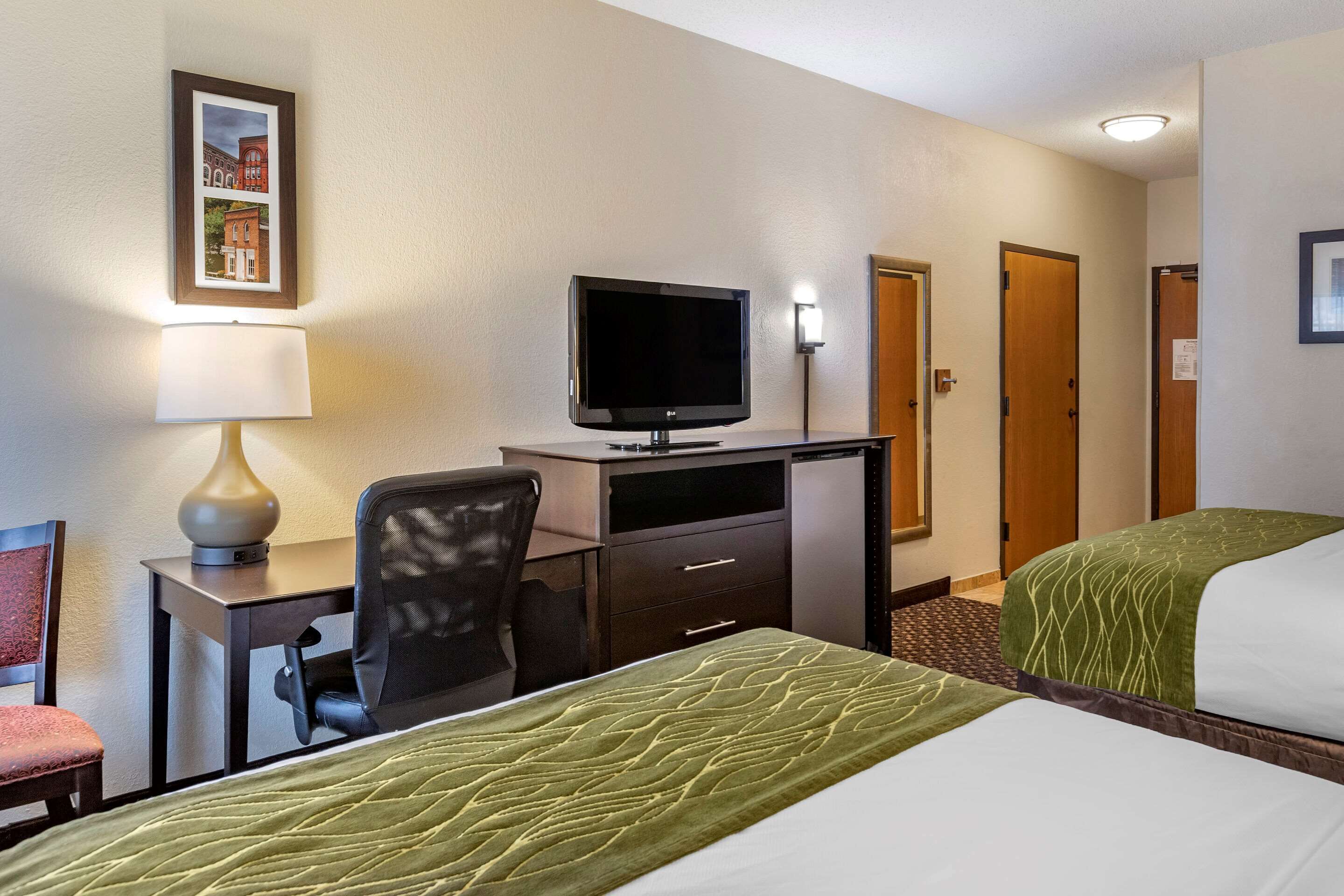 Une chambre d’hôtel avec deux lits, un bureau équipé d’une télévision, une chaise et une lampe.