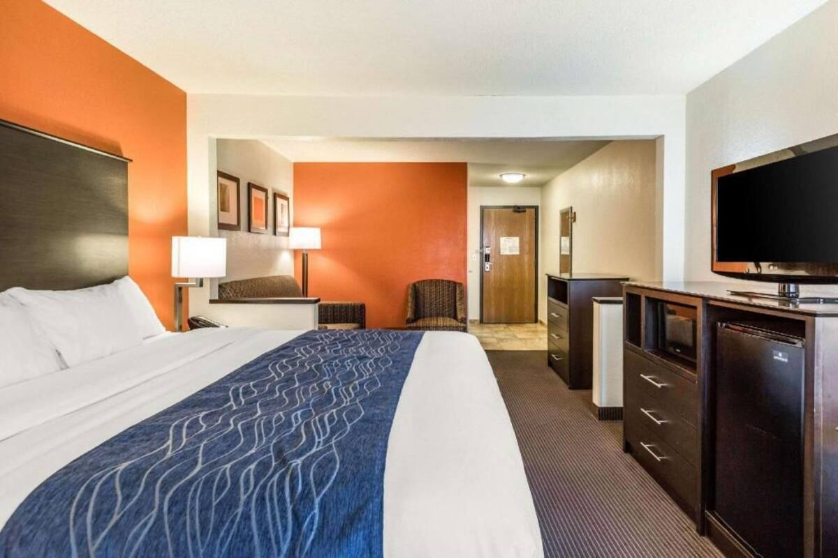 A hotel room with a bed, a desk, a television, and a wardrobe.