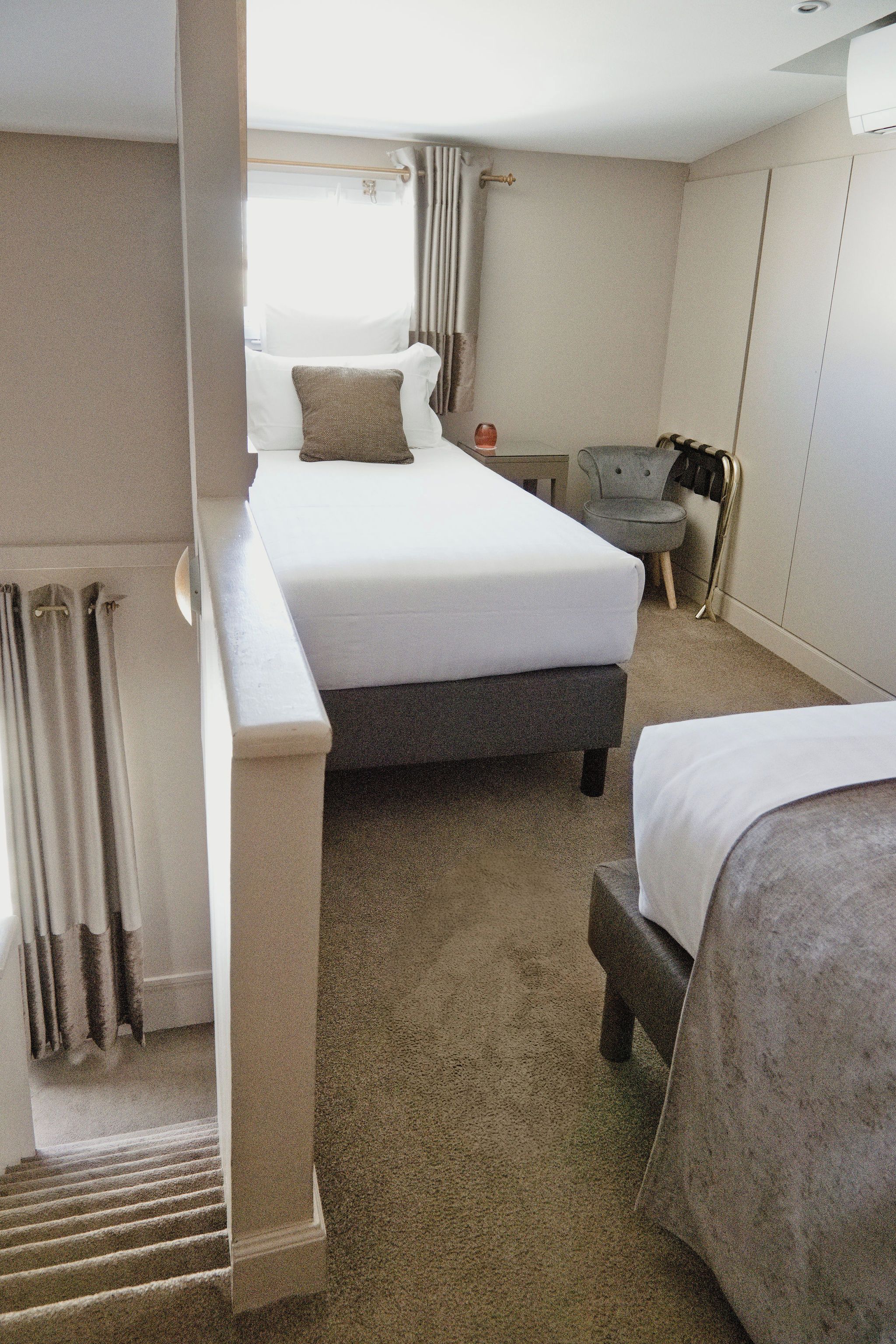 A hotel room with a bed, a chair, a small table, and a radiator.