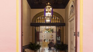 Een hotelentree met een betegelde vloer, een bankje, potplanten en een deur met een ruit.