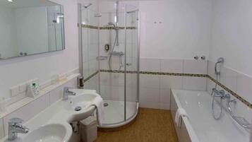 A bathroom with a glass-enclosed shower, a sink, and a bathtub.